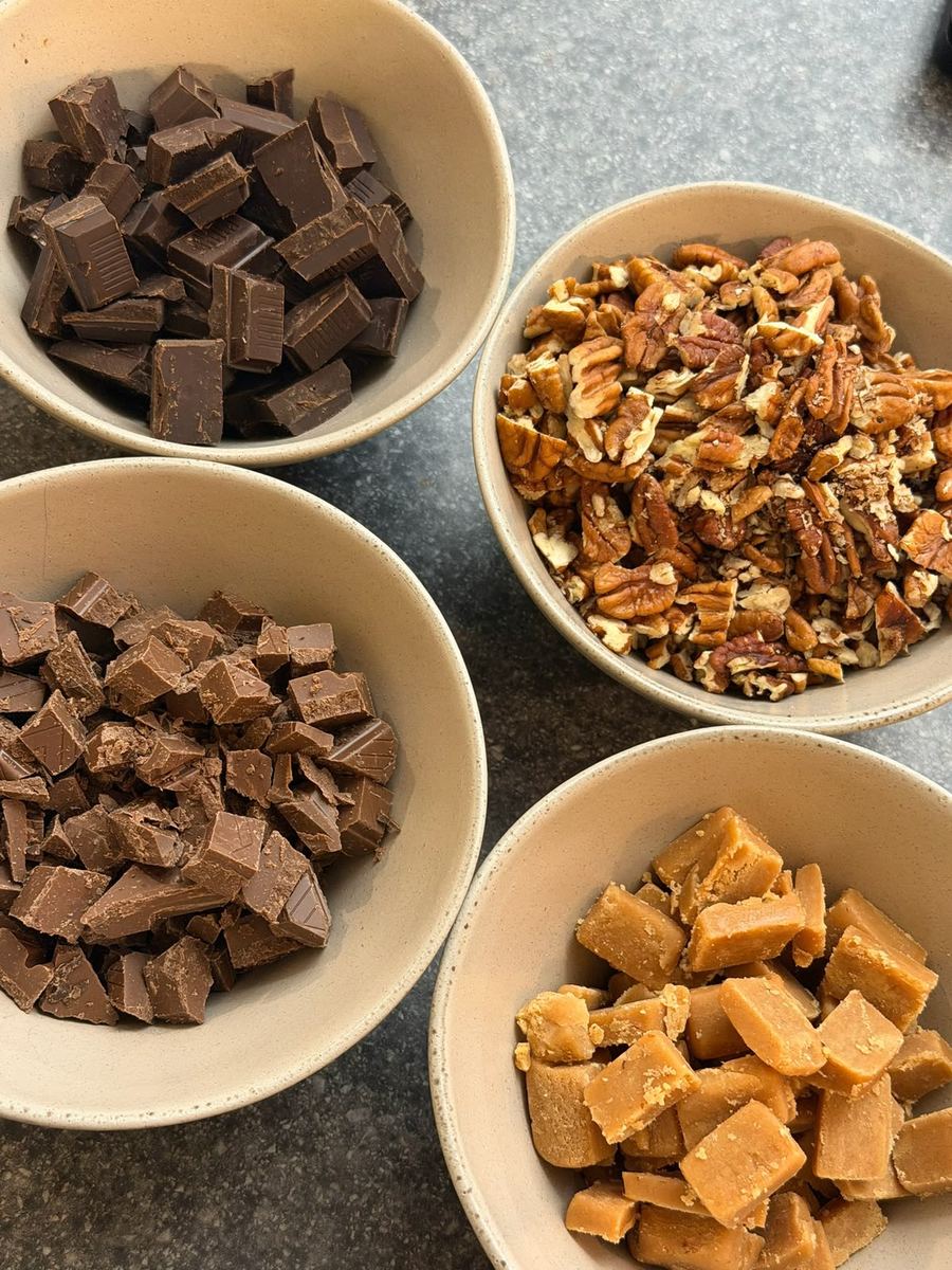 Bowls of chopped milk chocolate, dark chocolate, pecans and maple fudge cubes